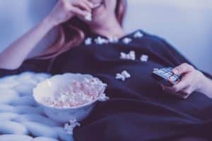 Woman Lying Eating Popcorn And Binge Watching TV